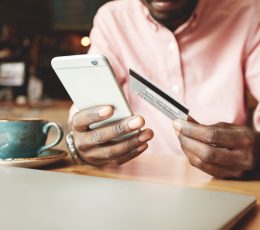 a man sitting at a table holding a smart phone.